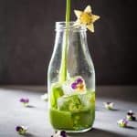 Green Smoothie being poured into a glass bottle decorated with a star-shaped kiwi slice.