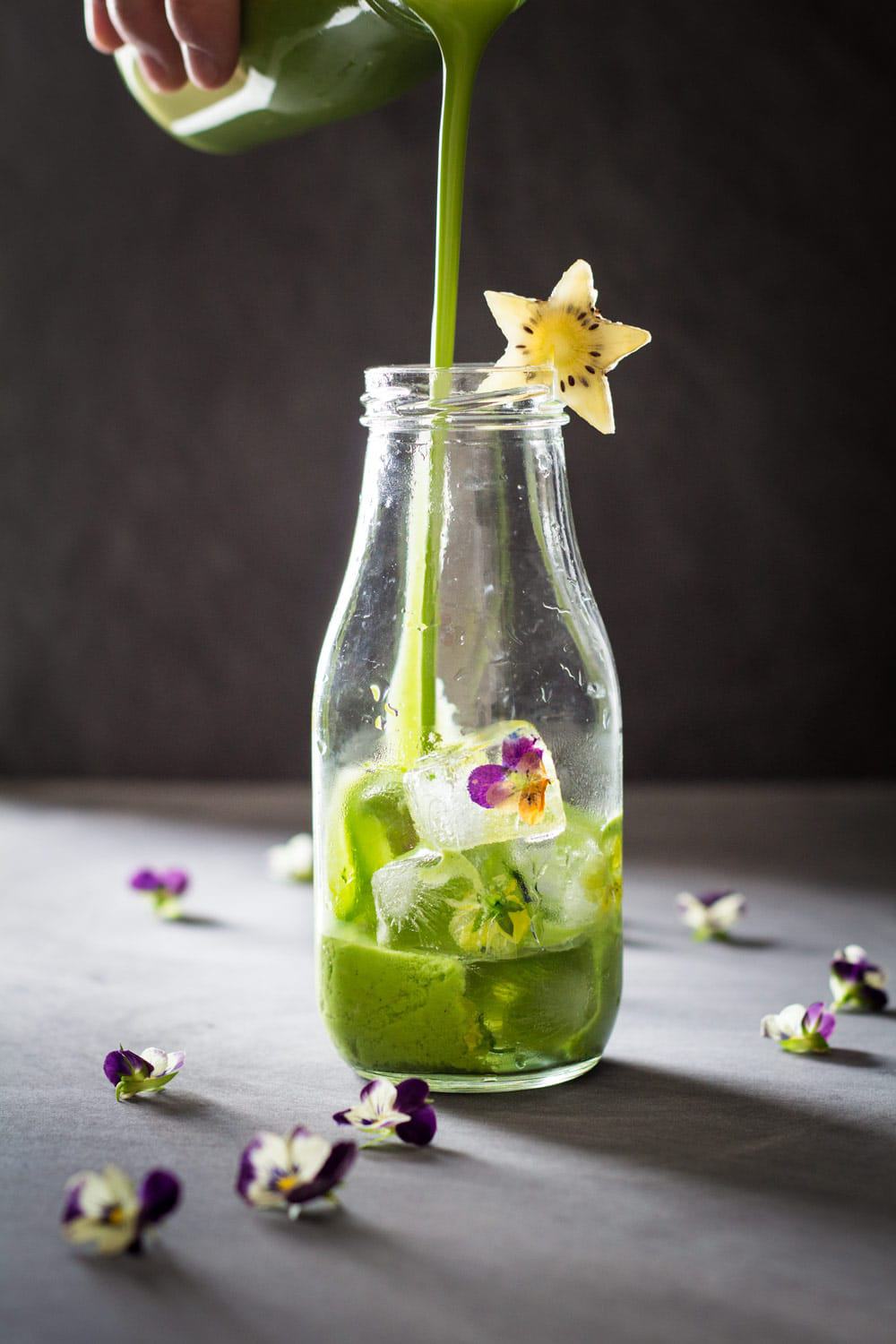Green Smoothie being poured into a glass bottle decorated with a star-shaped kiwi slice.