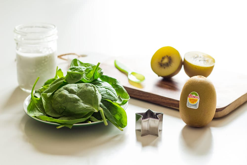 Ingredients for Green Smoothie For Kids. A glass of milk, spinach and kiwi.