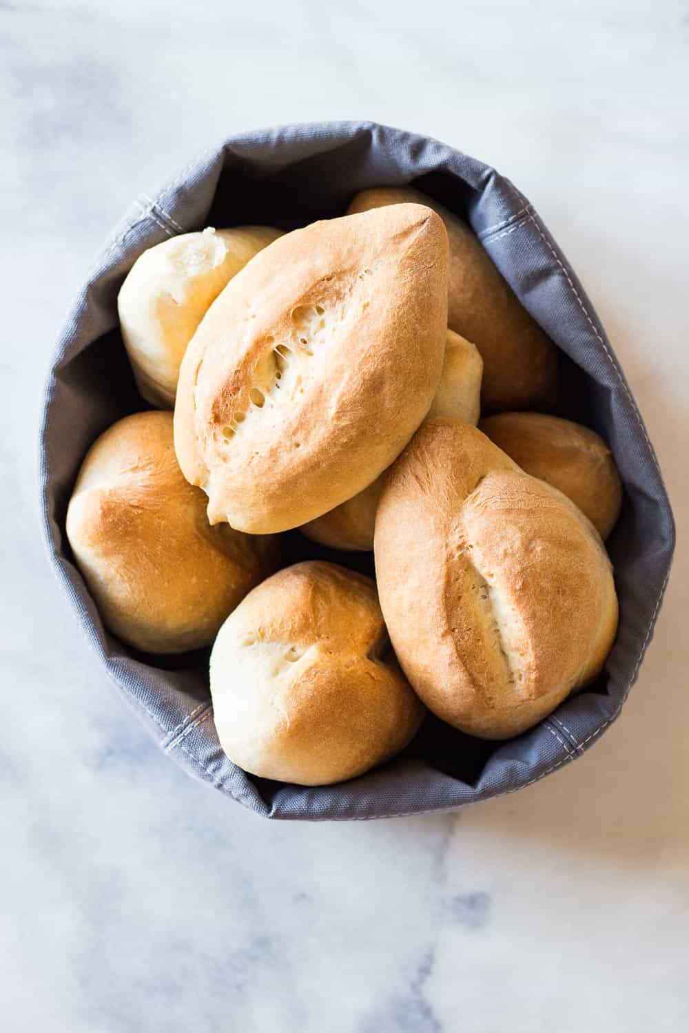 Dinner Rolls stacked on top of each other in a cloth bread basket.