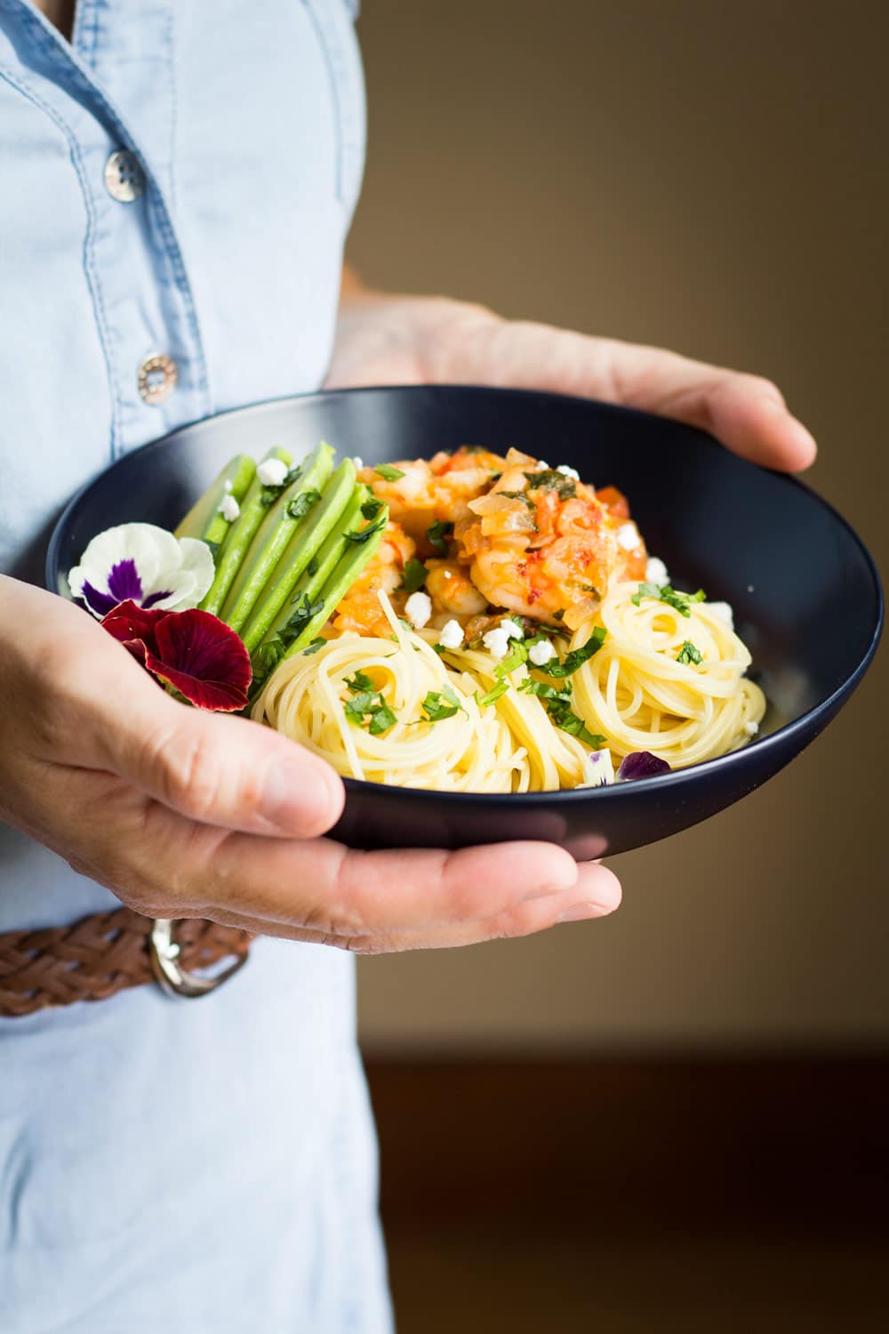 Person holding a bowl of Mexican-Style Shrimp Capellini Pasta.