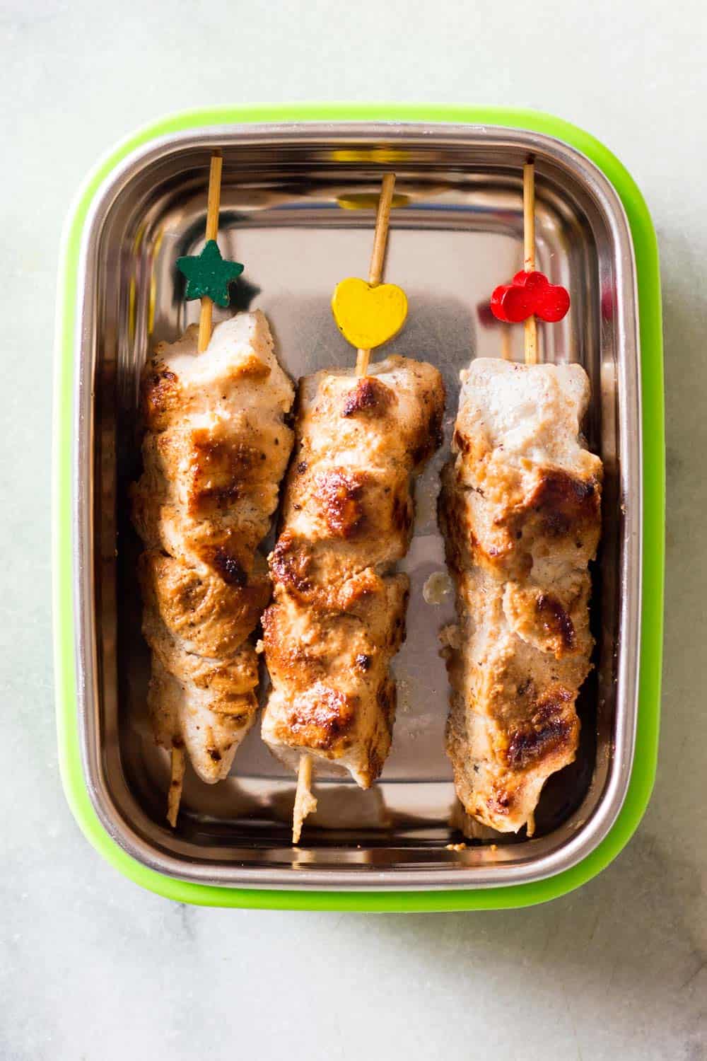 Three Middle-Eastern Grilled Chicken Skewers in a metal lunch container.