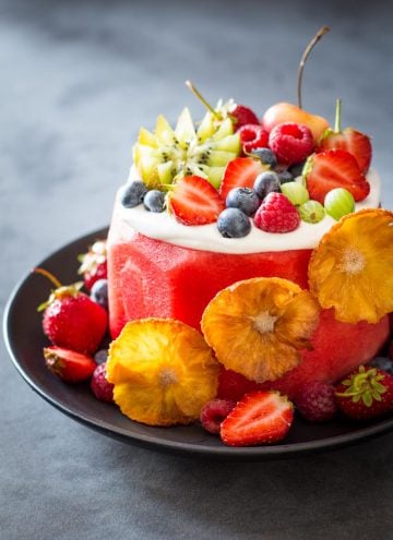Vegan Watermelon Cake on a black plate decorated with fresh fruit.