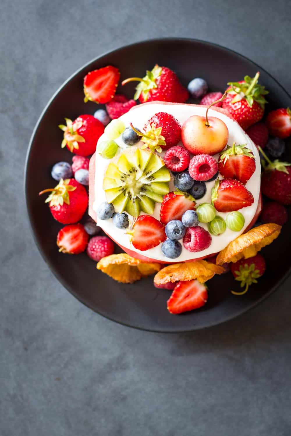 Top view of Vegan Watermelon Cake on a black plate decorated with fresh fruit.