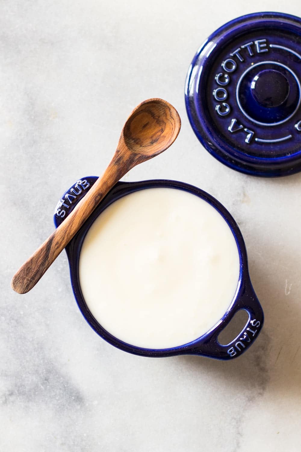 Yogurt Garlic Sauce in a blue ceramic dish with a wooden spoon.
