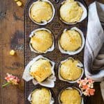 Cornbread muffins in parchment paper in a muffin tin.