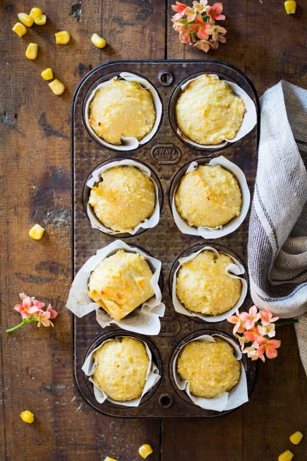 Cornbread muffins in parchment paper in a muffin tin.