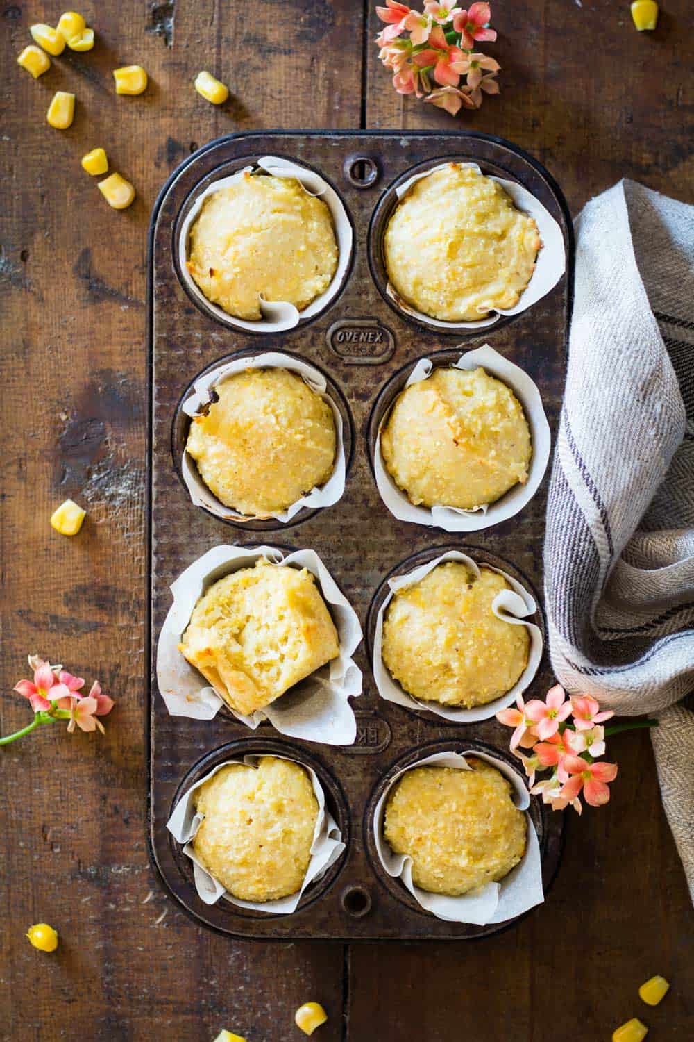 Cornbread muffins in parchment paper in a muffin tin.