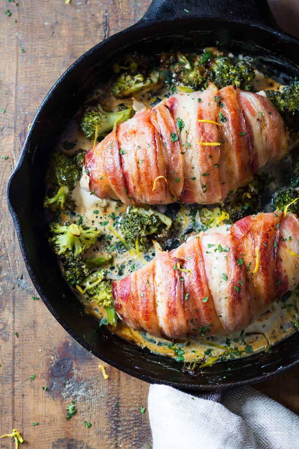 Bacon wrapped chicken breast in a pan with brocooli and creamy suace