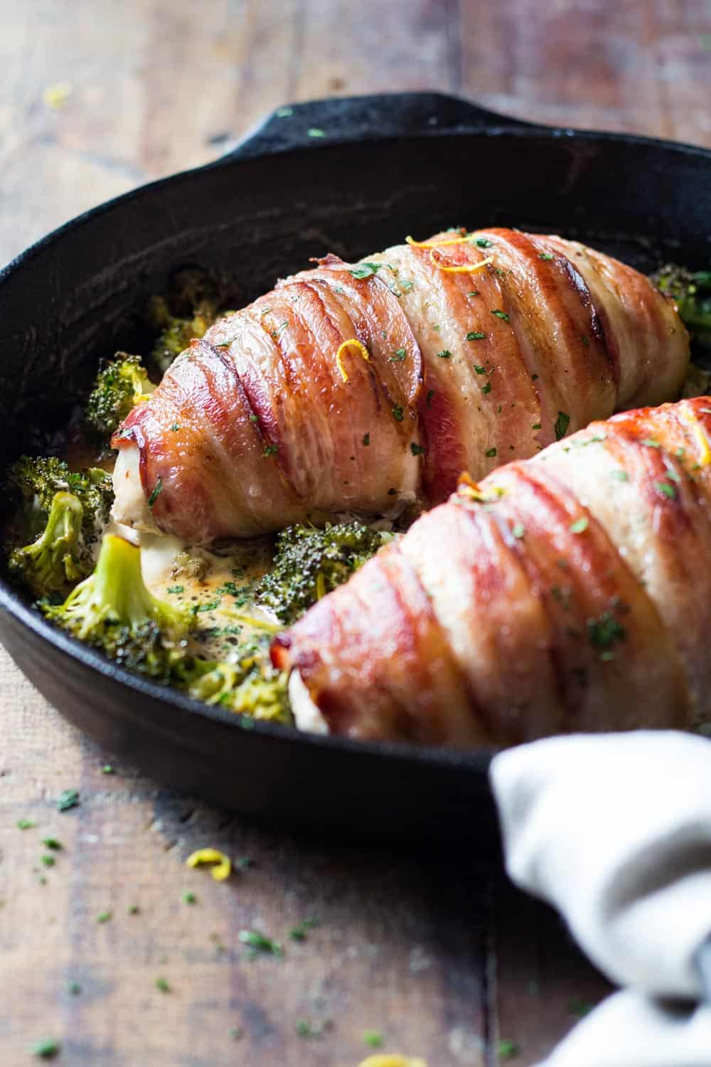 Bacon wrapped chicken breast recipe in a cast iron skillet with broccoli.