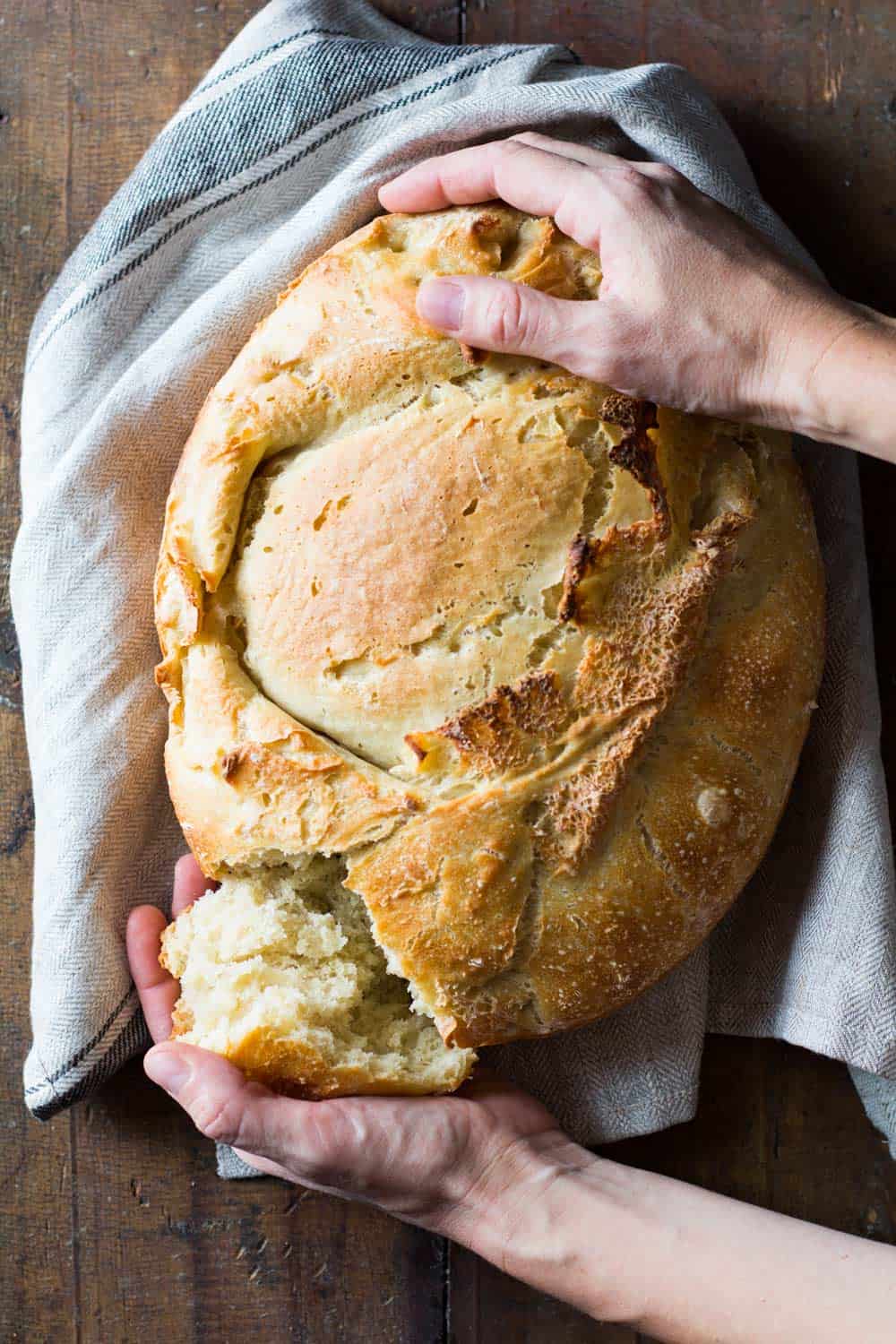 Apple Yeast Bread on dish cloth with hands pulling apart a piece.