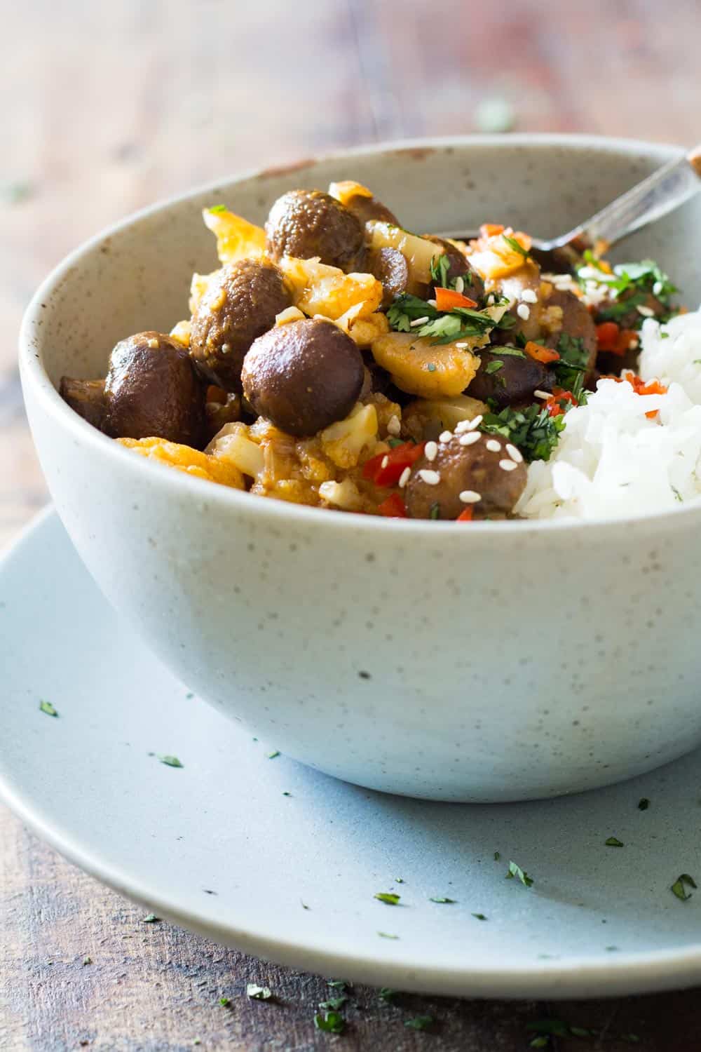 Vegan yellow curry with white rice served in a bowl on a plate. 