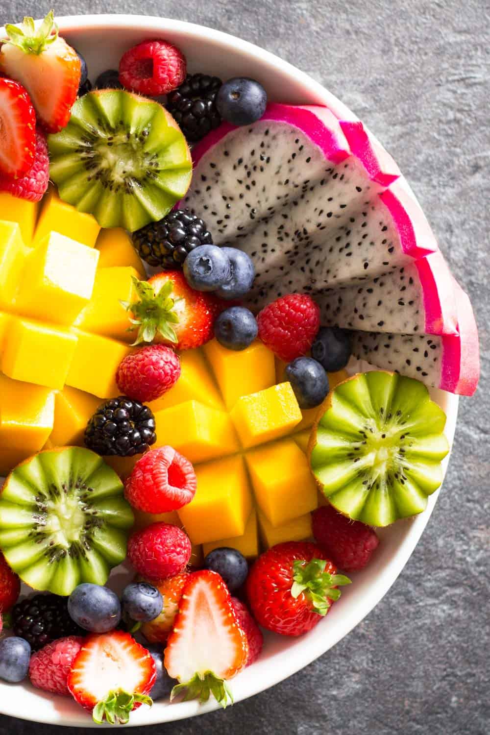 Detail of fruit platter which includes strawberries, raspberries, blueberries, blackberries, kiwis, dragon fruit, and mango.