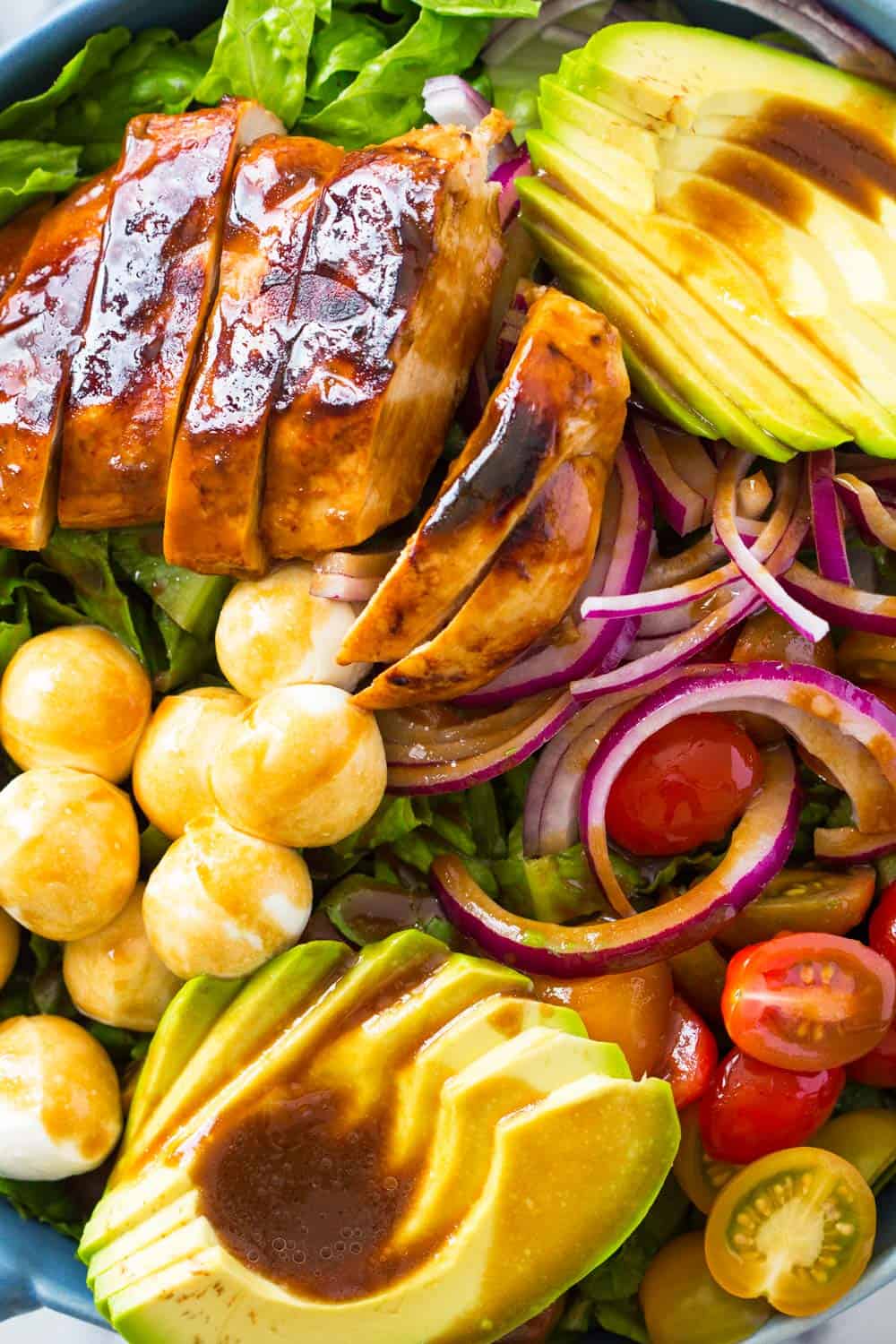 Honey mustard chicken breast sliced, with avocado, cherry tomatoes, onion, chickpeas and lettuce leaves drizzeled with honey mustard dressing. 