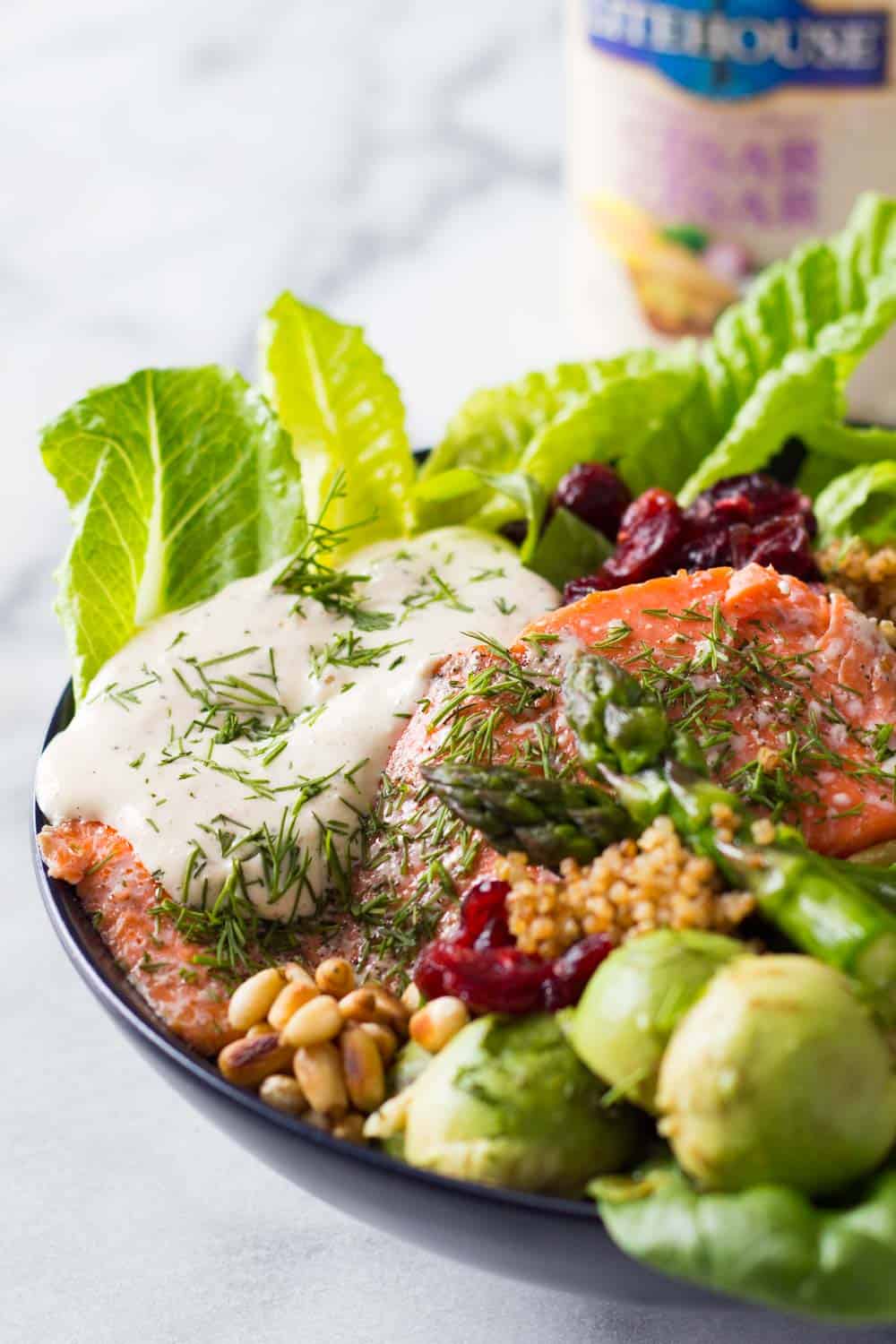 Baked Sockeye Salmon topped with creamy caesar dressing and served with lettuce leaves, dried cranberries, pine nuts, asparagus, avocado balls and quinoa.