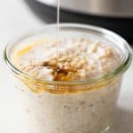 An Instant Pot in the background and cooked steel cut oats in a jar in front.