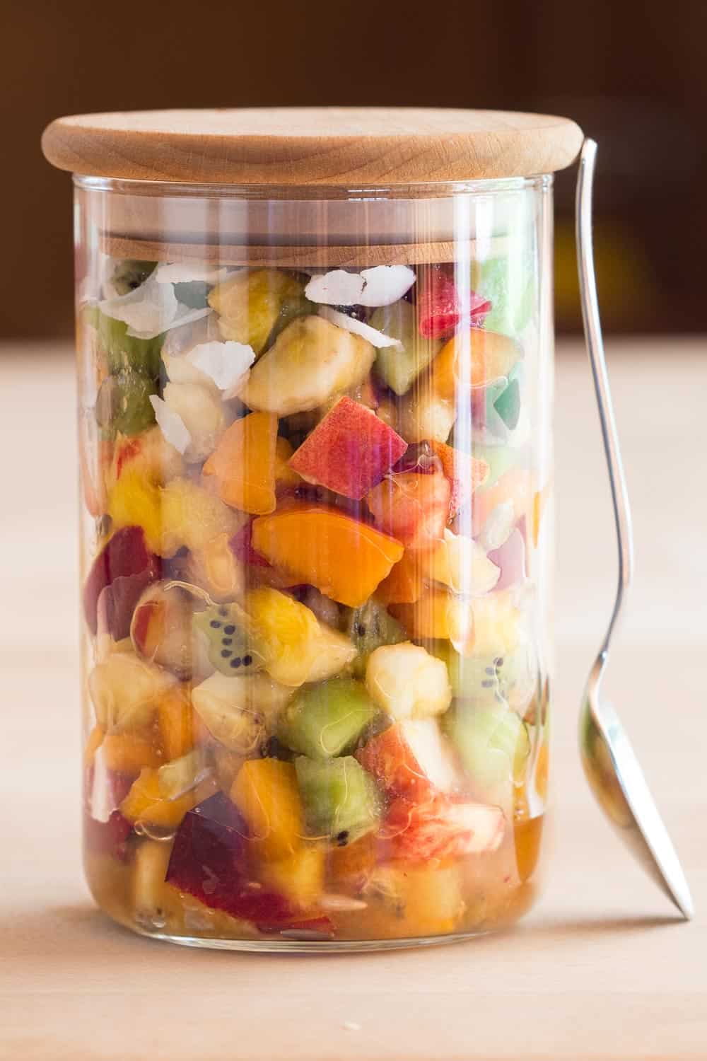 Mango Fruit Salad in a jar with a spoon leaning against it.