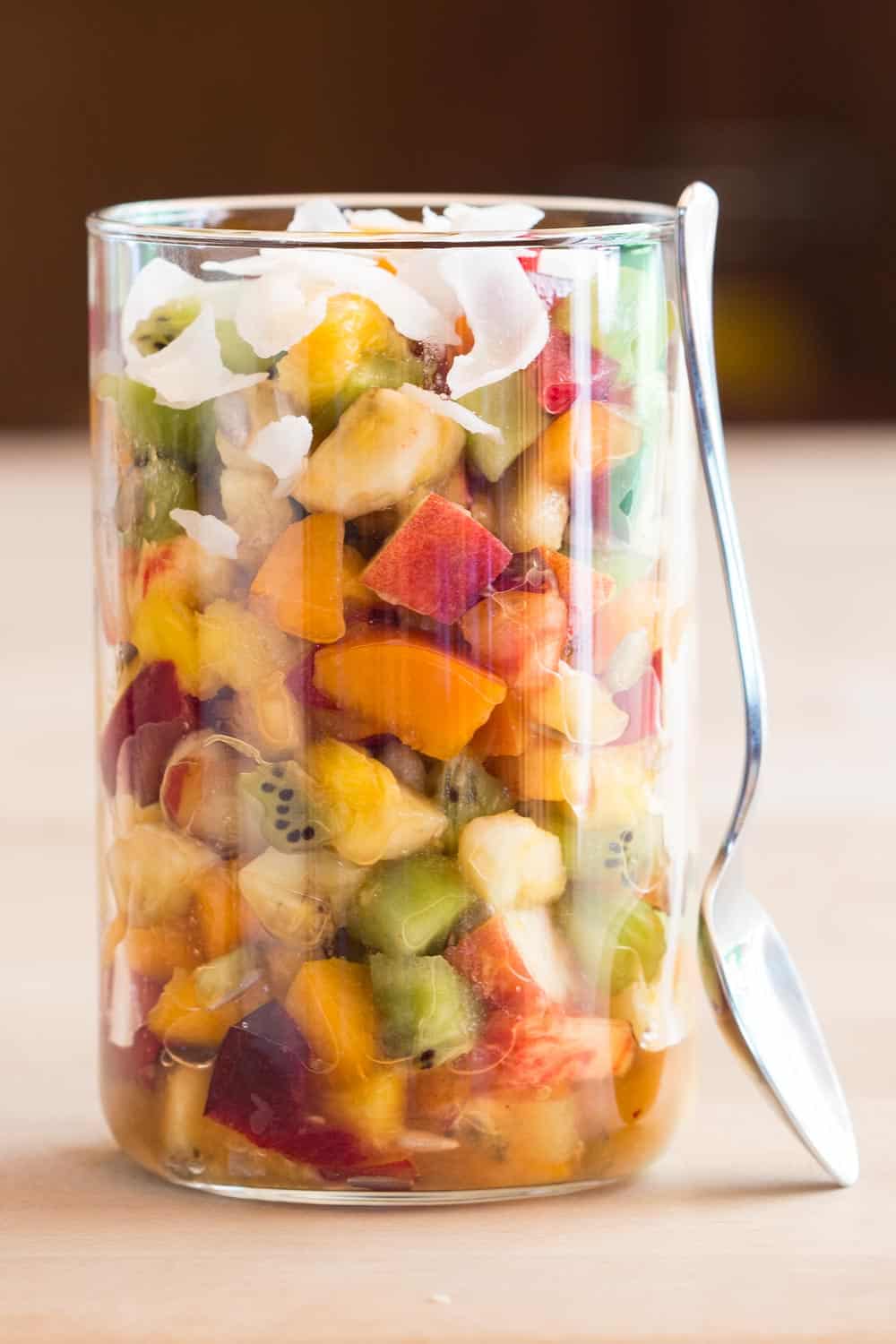 Mango Fruit Salad in a jar with a spoon leaning against it.