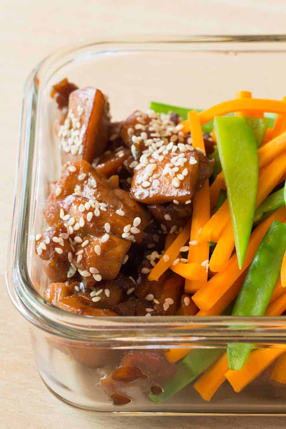 Close up of meal prep bowl showing texture of vietnamese chicken sprinkled with sesame seeds and veggies on the side