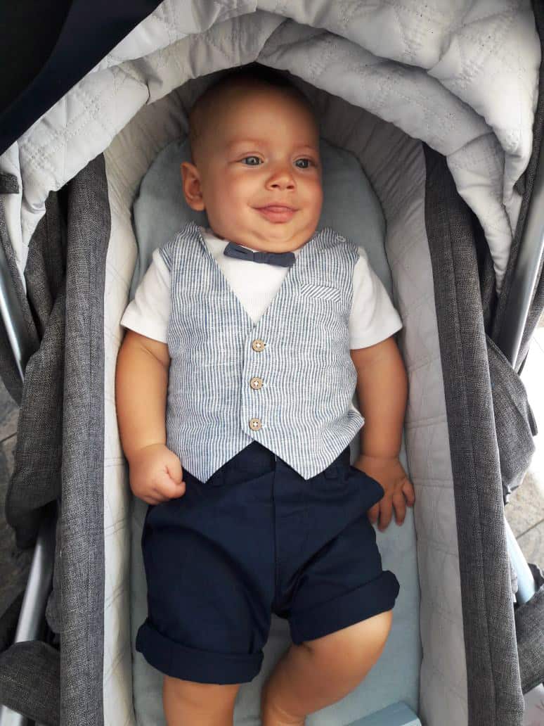 A dressed-up baby in a bassinet.