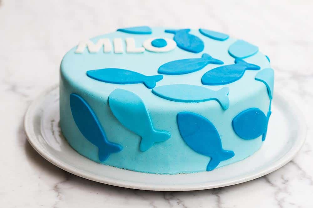 Side view of a blue cake decorated with blue frosting fish.