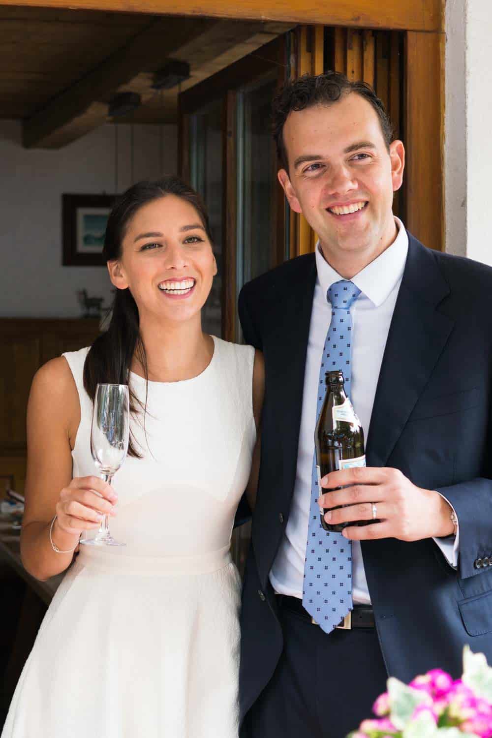 A couple on their wedding day smiling and making a toast.