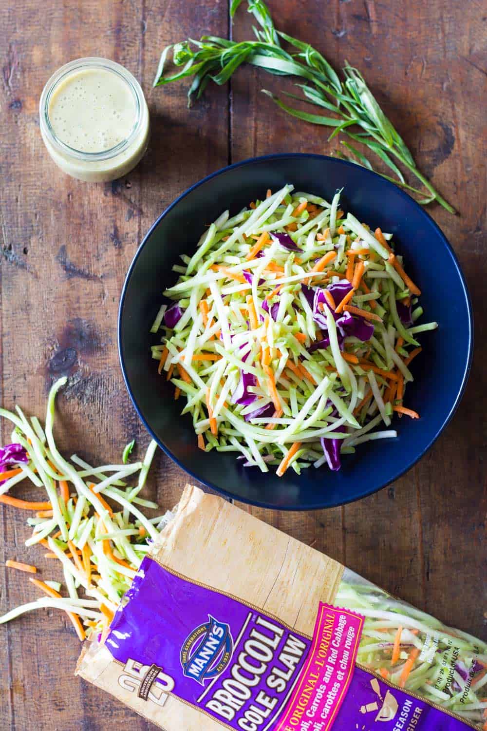 Mann's broccoli slaw opened package, a blue plate with slaw and an opened jar of dressing 