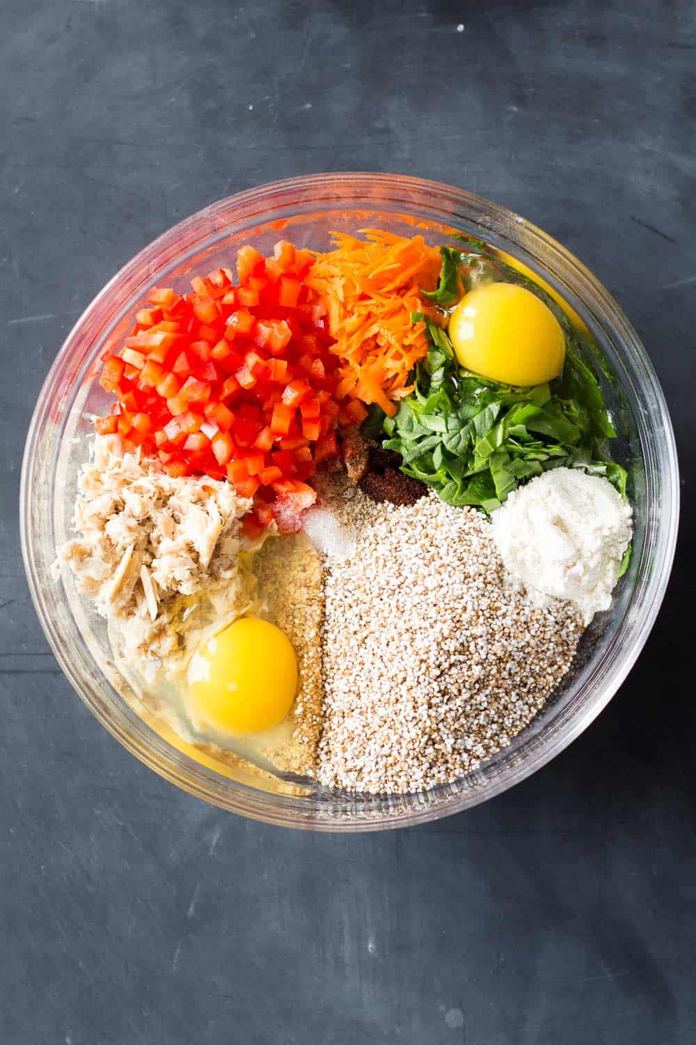 Ingredients for healthy Tuna Patties in a bowl. Puffed Amaranth, Eggs, Tuna, Chopped Bell Pepper, Grated Carrot, Chopped Baby Spinach, Flour, Chipotle Powder, Sea Salt, Pepper. 