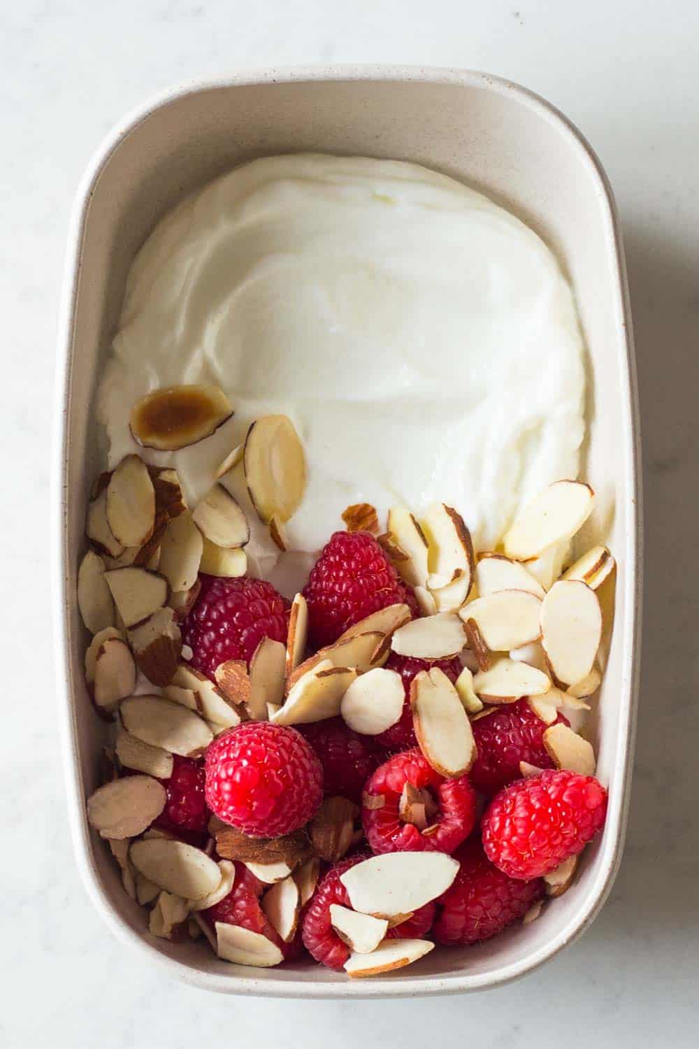 A healthy keto breakfast as for a complete keto diet plan - unsweetened full fat greek yogurt topped with raspberries and sliced almonds.