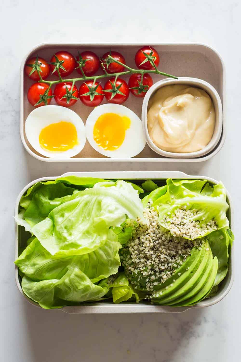 A healthy keto dinner for a complete keto diet plan- butter lettuce, avocado, hemp seed salad with mayonnaise, a soft boiled egg and cherry tomatoes.