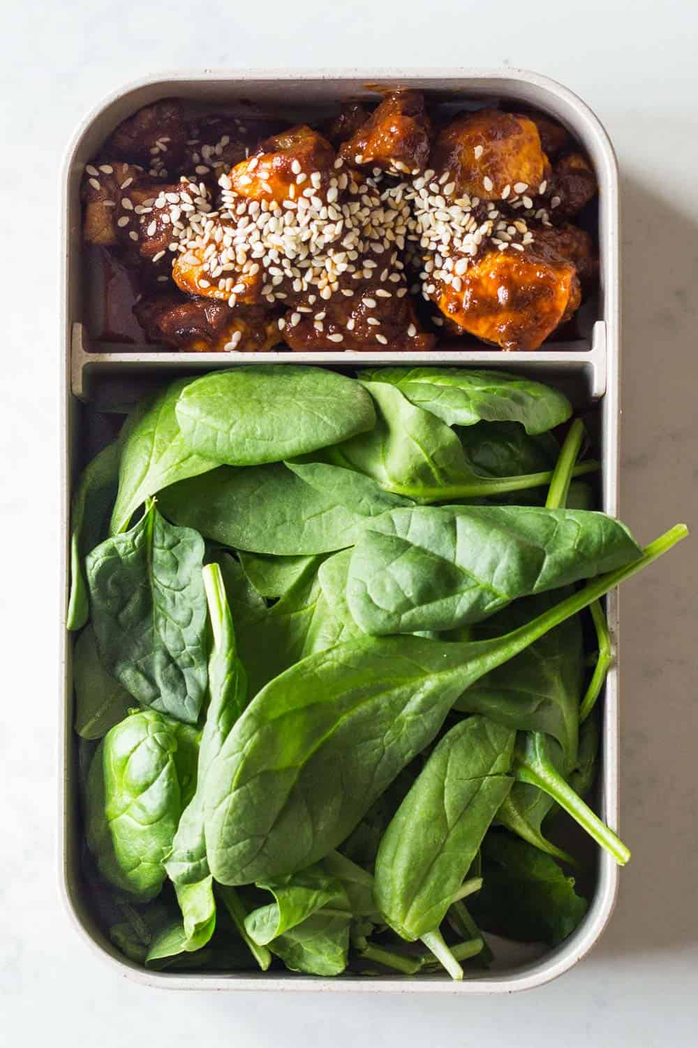 A healthy keto lunch for a complete keto diet plan - chicken curry made with coconut oil and full fat coconut milk, topped with sesame seeds and baby spinach on the side.