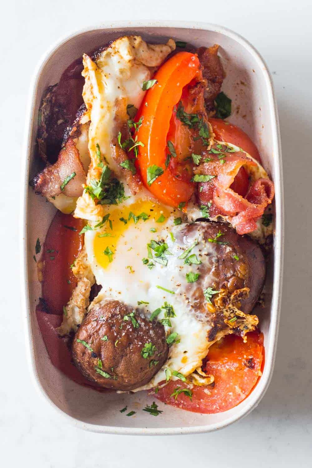 A healthy Paleo breakfast for your Paleo Meal Plan - bacon, tomato, mushrooms, eggs and parsley.