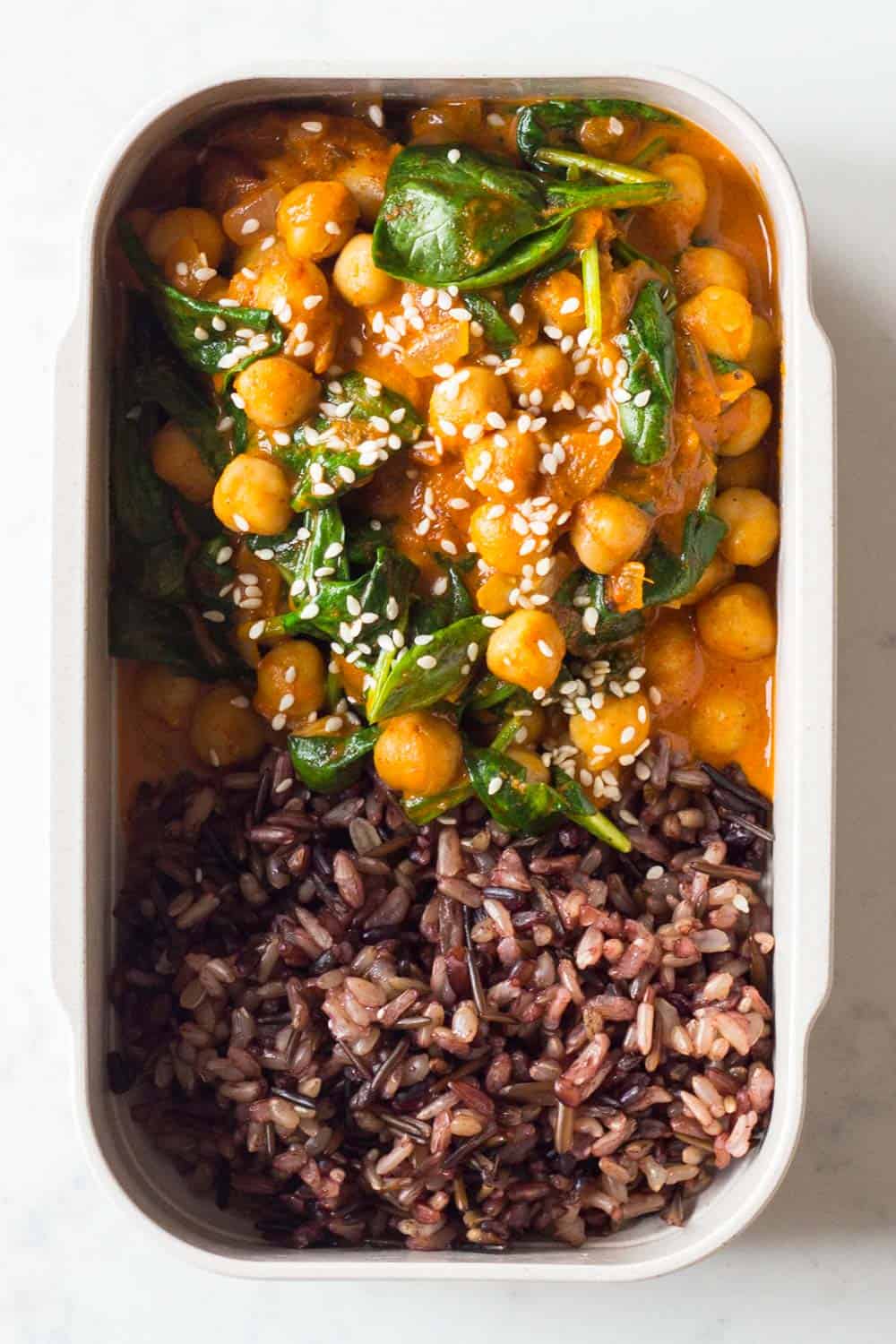 Meal prep container filled with chickpea spinach curry and with wild rice blend.