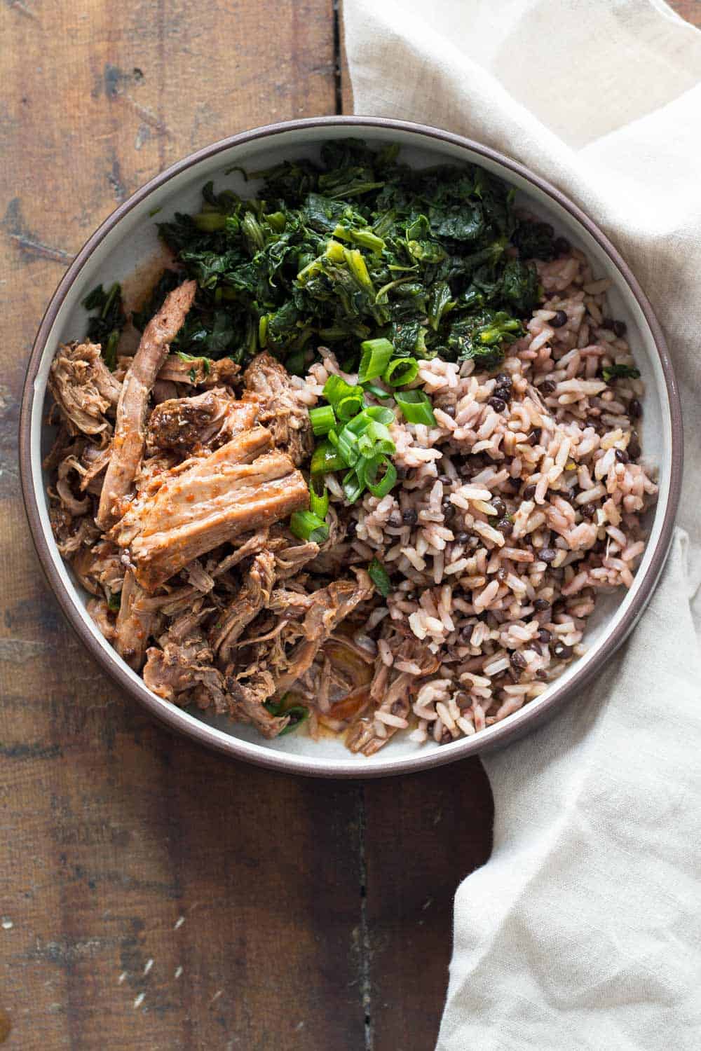 A plate with Slow-Cooker Pot Roast, brown rice, puy lentils, and sautéed spinach.