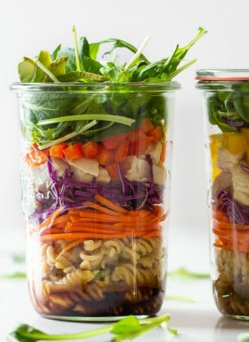 Chicken Pasta Salad in a Jar fille din layers of dressing, pasta, carrot, cabbage, bell pepper, lettuce.