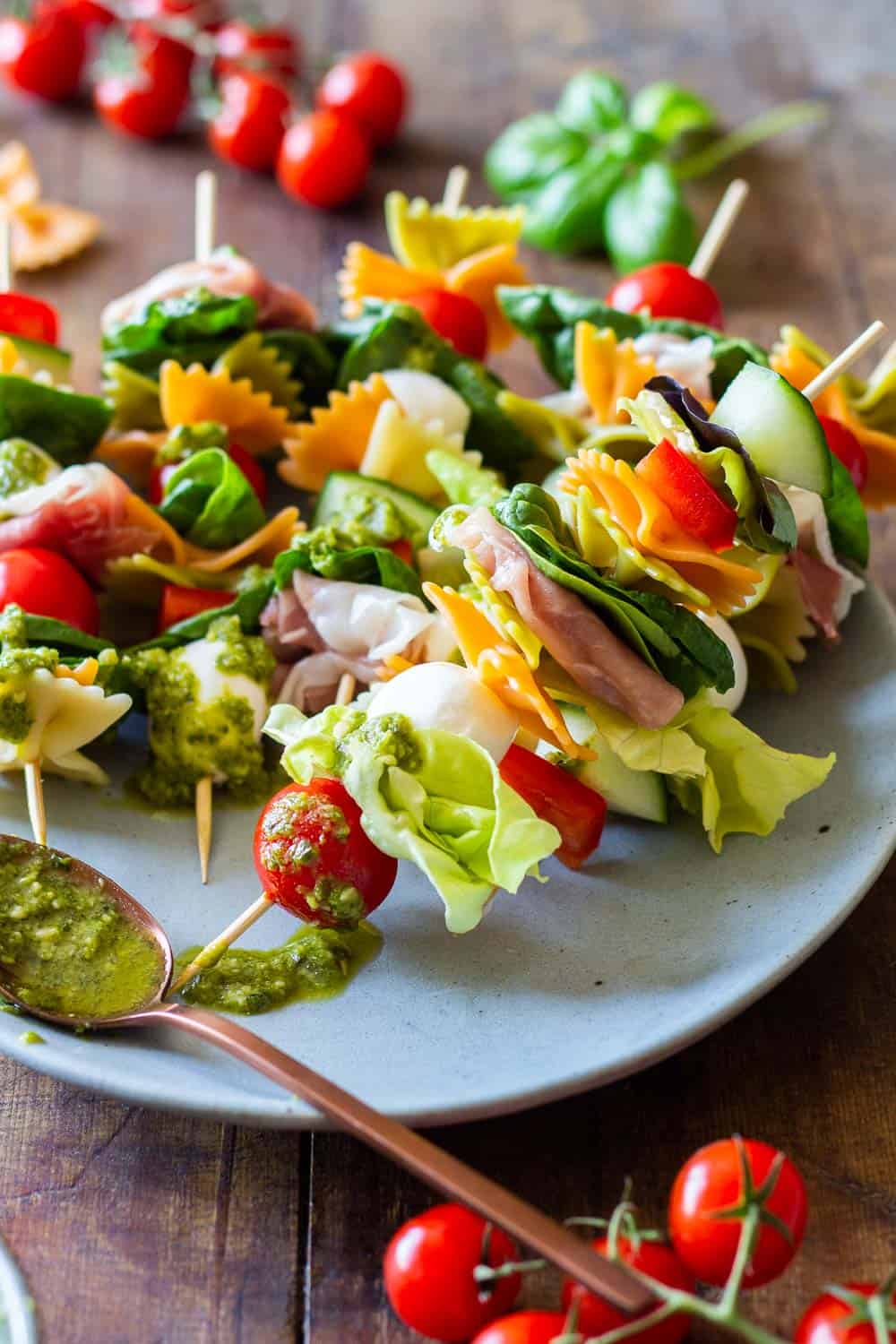 Antipasto Appetizer Skewers arranged on a plate and green pesto on a spoon