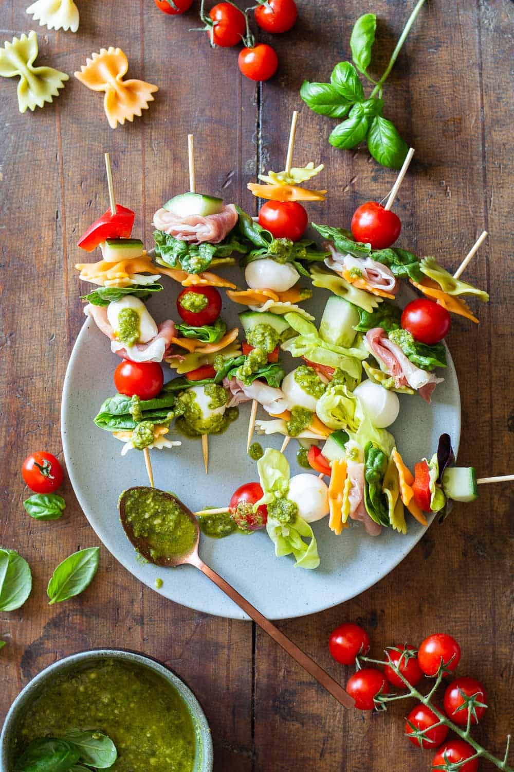 Antipasto Skewers drizzeled with green pesto on a plate