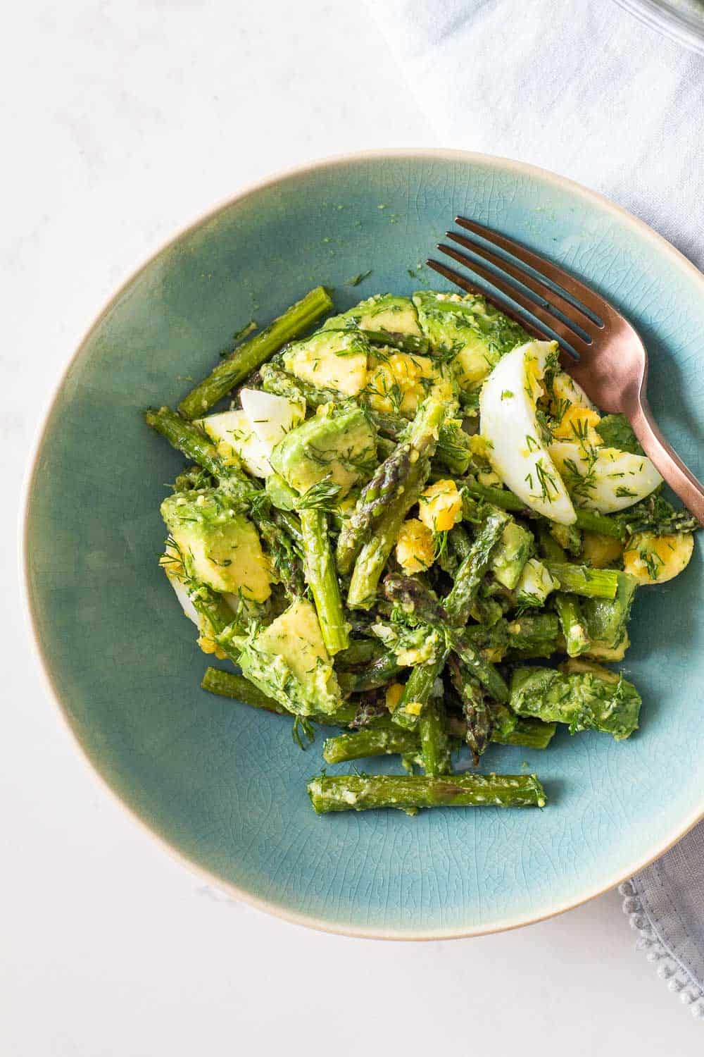 Egg Salad with Avocado in a aqua-colored large bowl with fork.