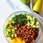 Cucumber Avocado Salad with crispy spicy chickpeas in a glass bowl next to a pale blue napkin
