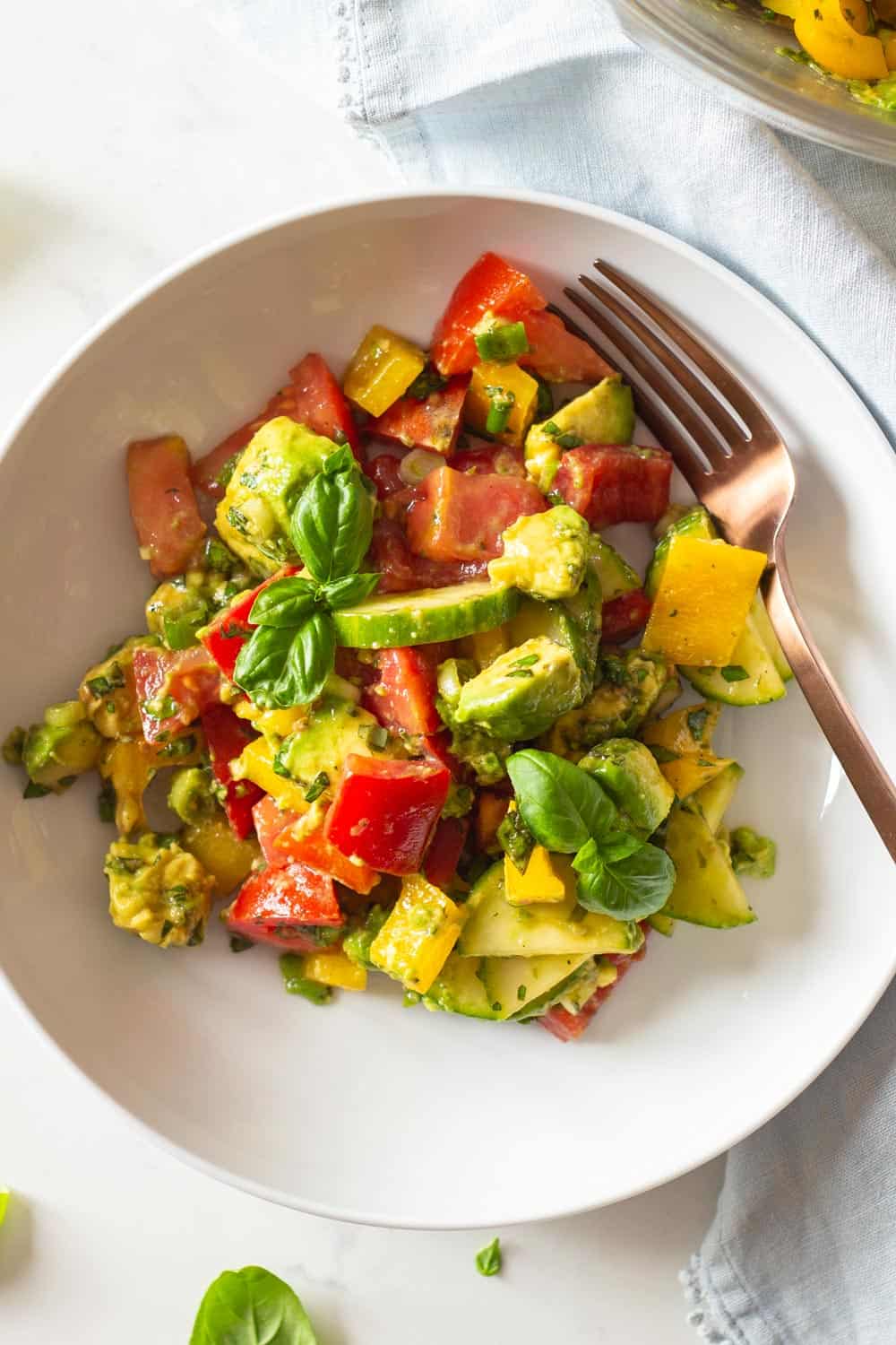 Tomato Cucumber Avocado Salad mixed up and served in a white salad bowl