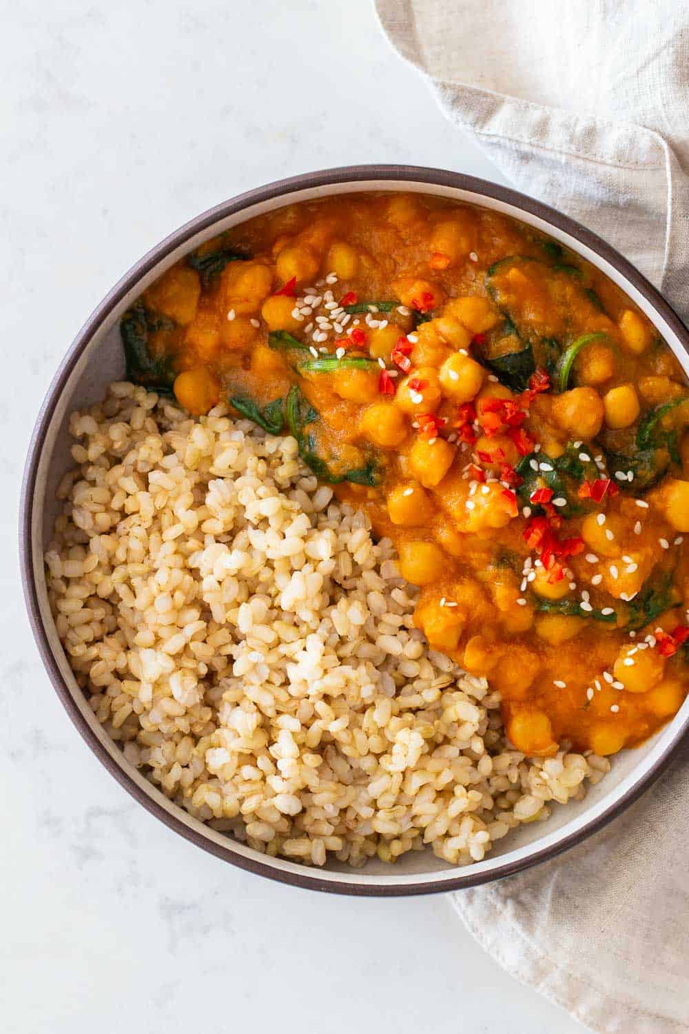 Sweet Potato Curry with chickpeas and baby spinach made in Instant Pot served with brown rice in a round bowl.