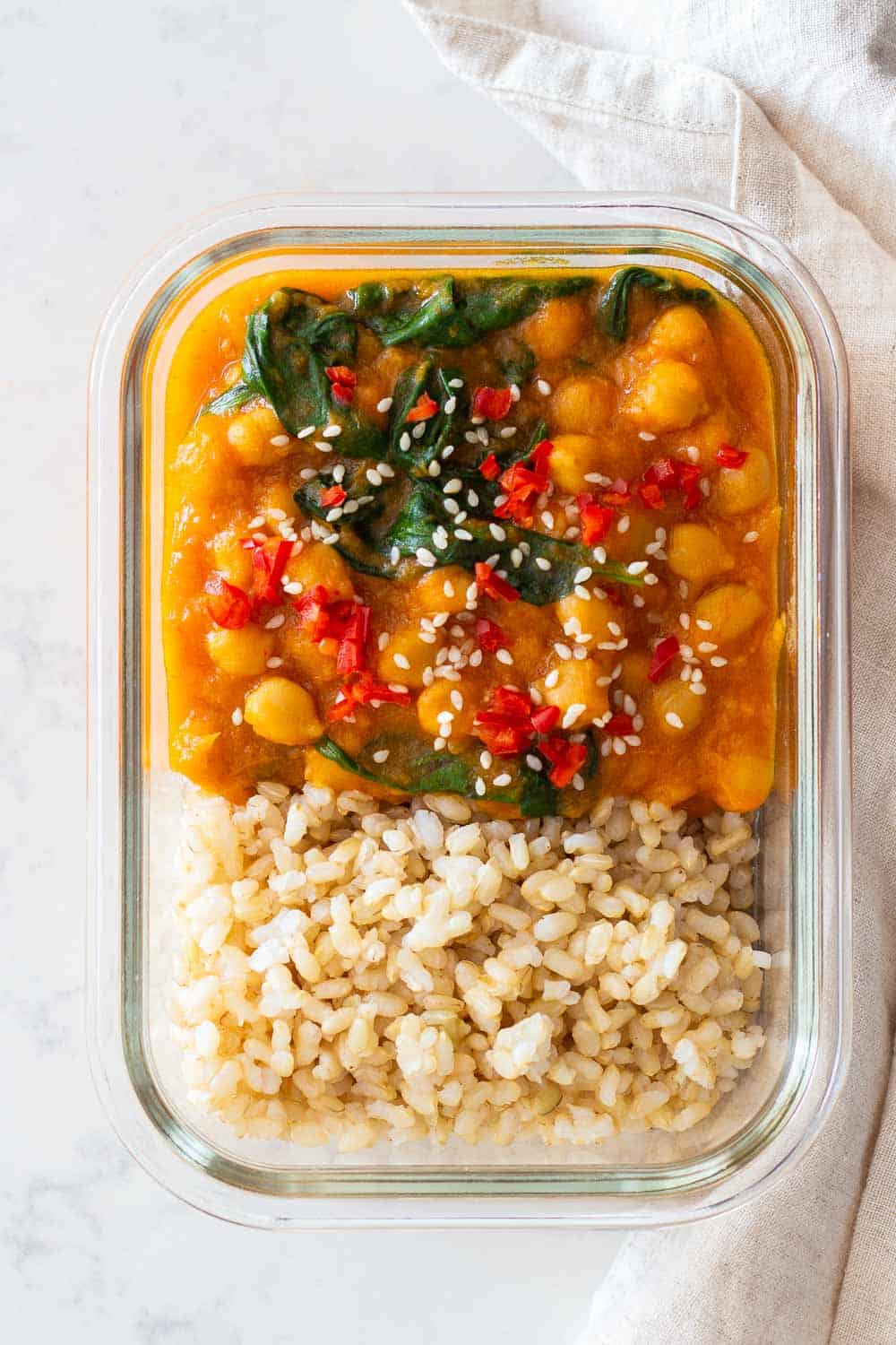 Chickpea Sweet Potato Curry with baby spinach served in meal prep container with brown rice