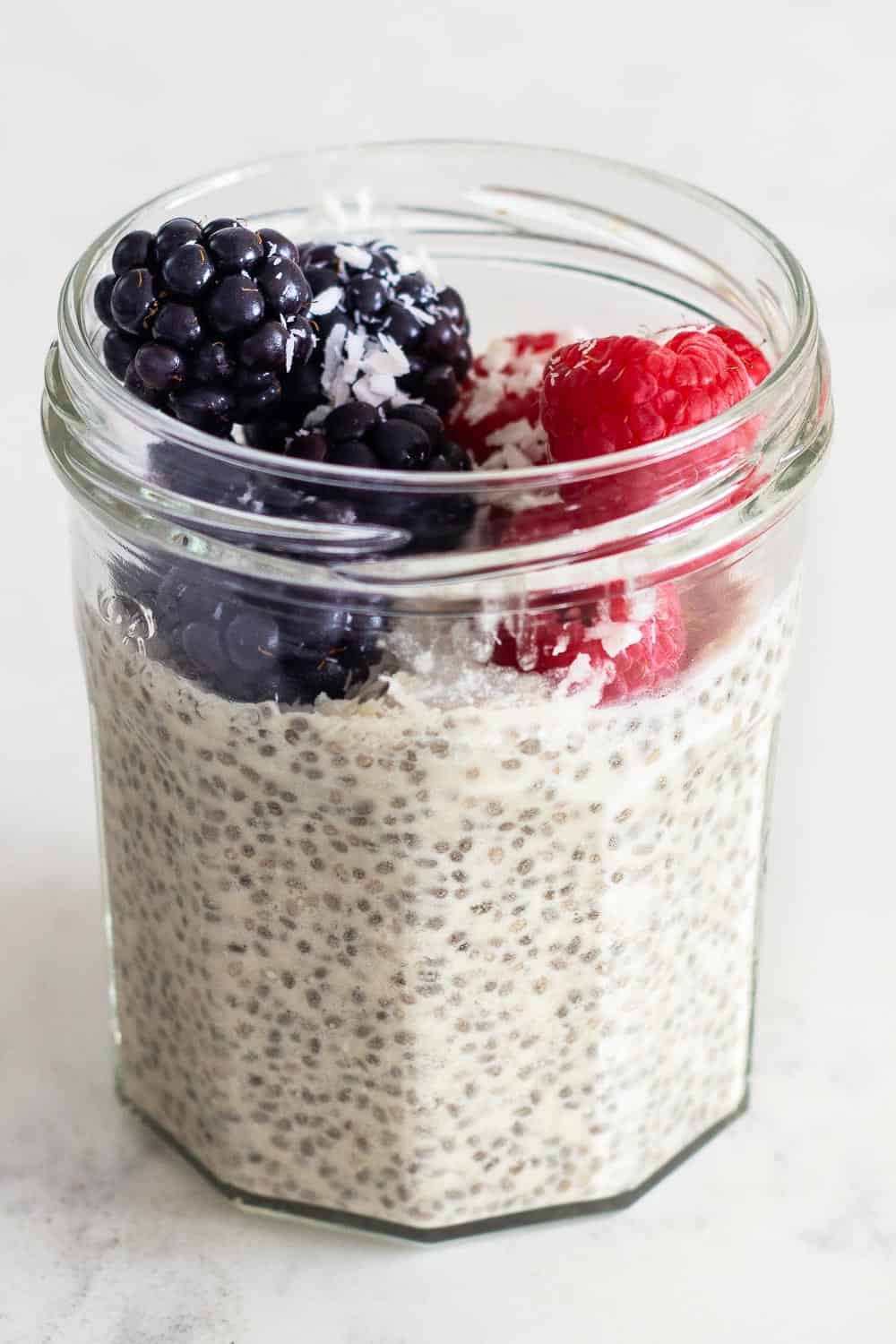 Coconut milk Chia Seed Pudding in a glass jar topped with blackberries and raspberries.