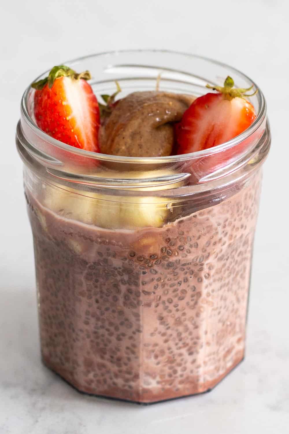 Chocolate Chia Seed Pudding in a glas jar topped with banana, strawberry and almond butter