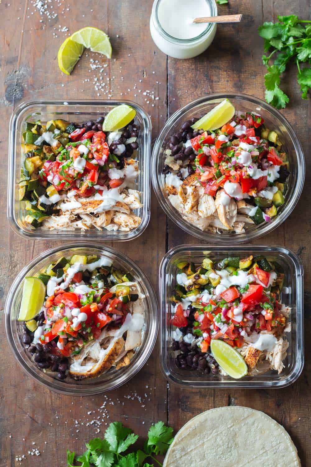 Four Mexican Chicken Meal Prep Containers on a wooden table.