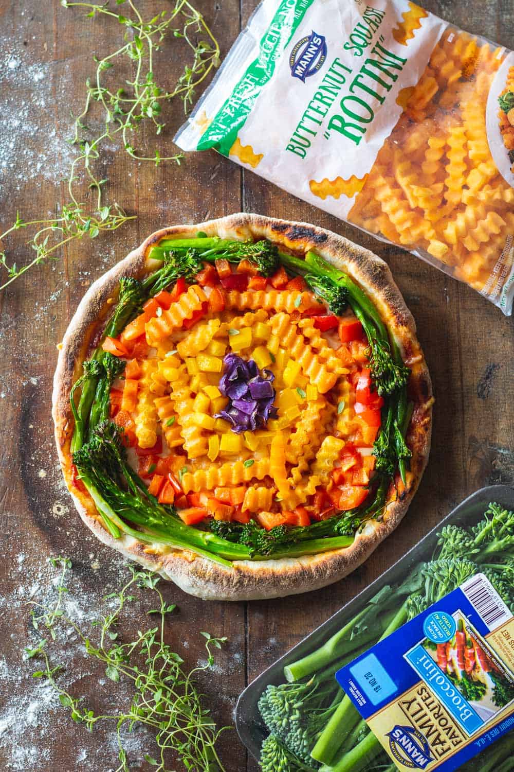 Mann's Broccolini and Mann's Butternut Squash Rotini Bags around rainbow pizza