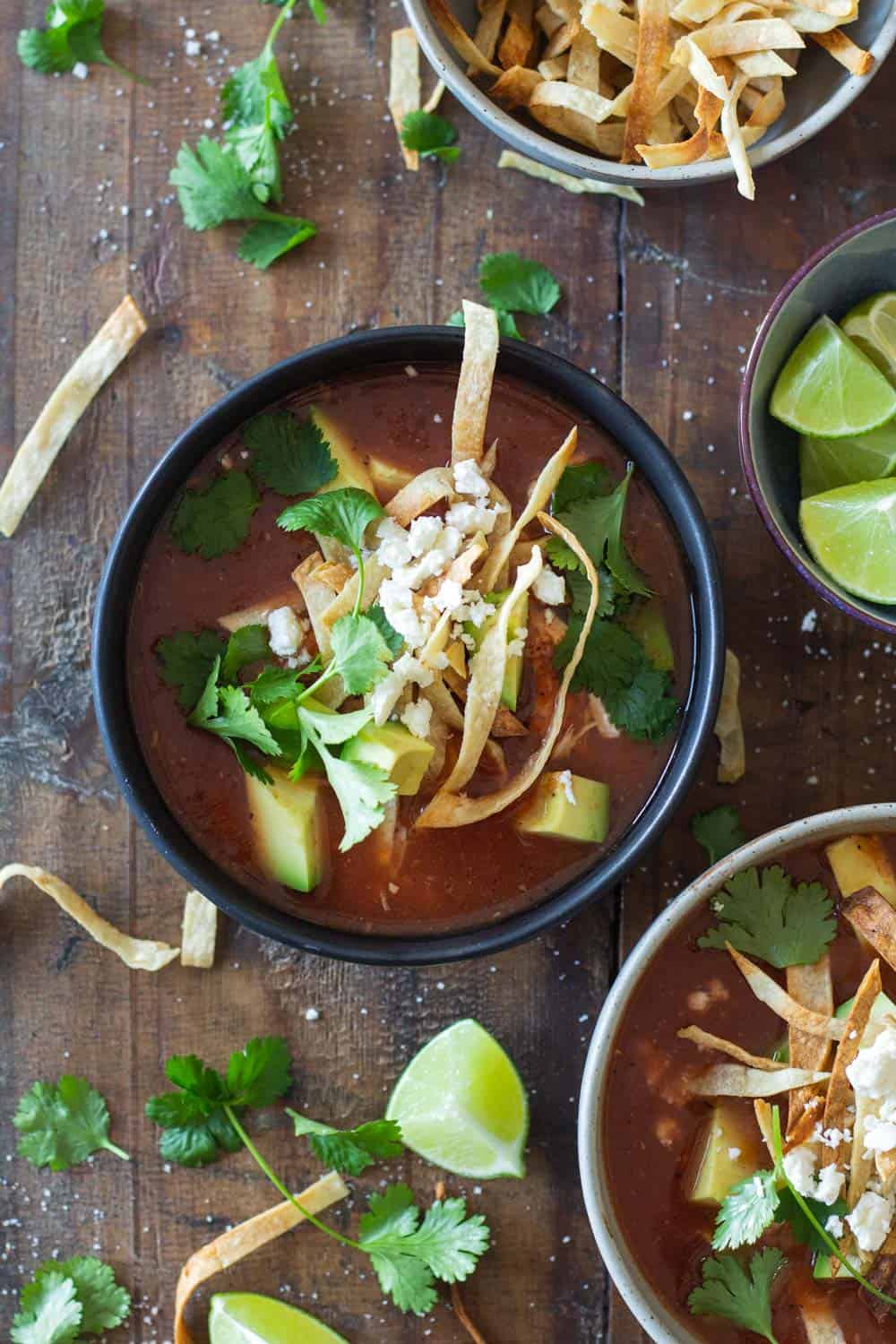 Crock Pot Chicken Tortilla Soup topped with crispy tortilla strips, avocado, cilantro and queso fresco