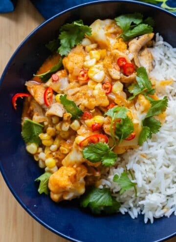Thai Chicken Cauliflower Curry next to white rice in a blue serving bowl.