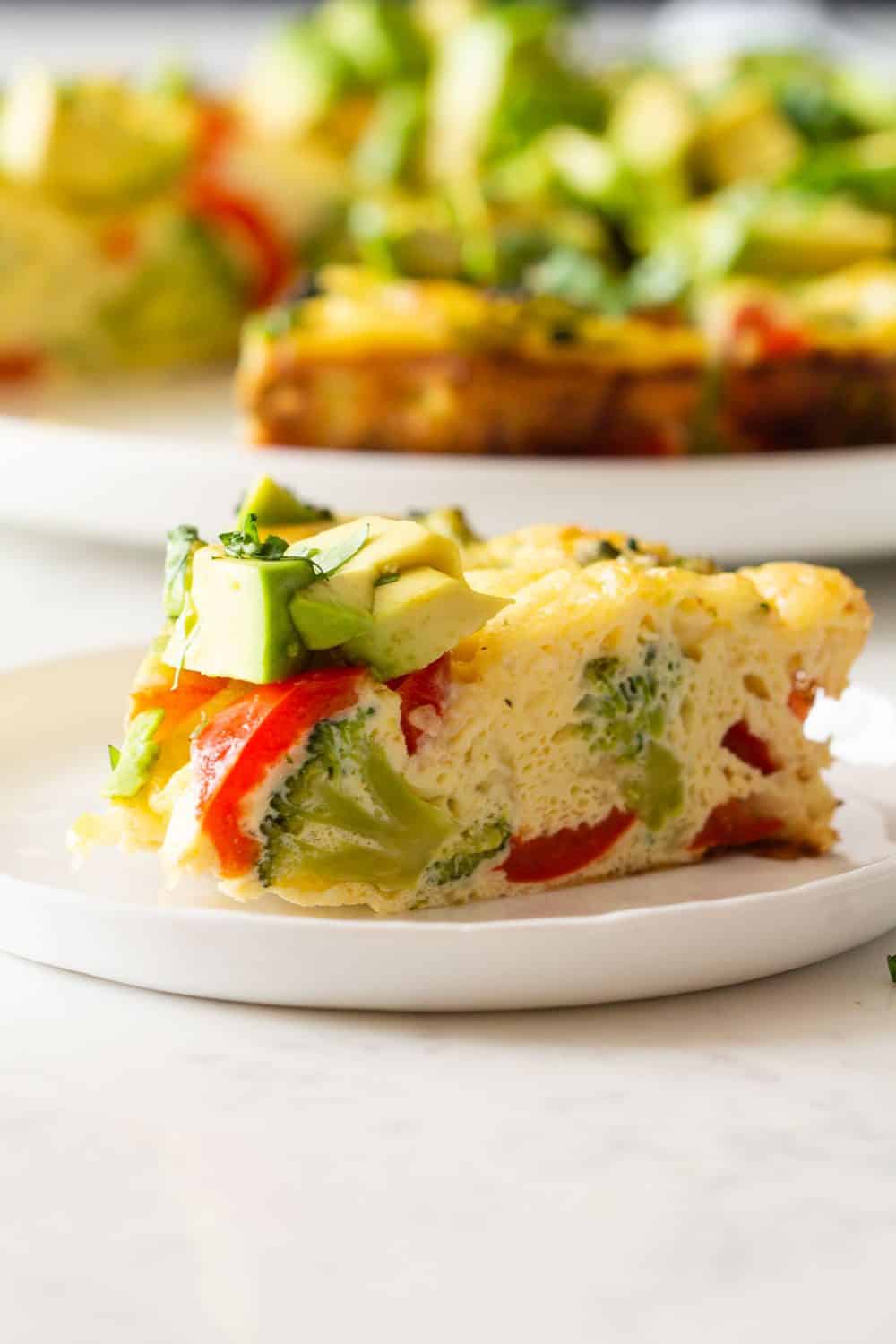 Slice of vegetable frittata on a plate showing inside texture.