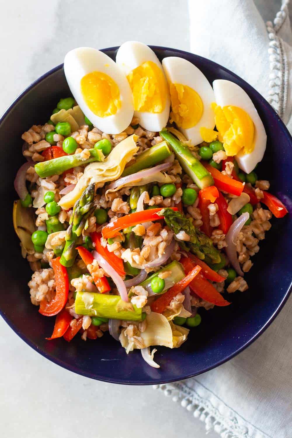 Farro Spring Salad in a bowl with hard boiled eggs on top